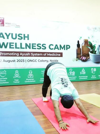 Demonstrating Adho Mukha Svanasana (Downward-Facing Dog) at the ONGC wellness camp. This pose energizes the body and calms the brain.