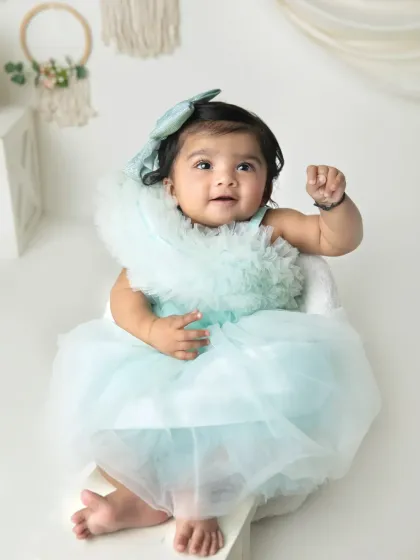 A sweet, happy expression from this little girl in her pretty dress. The simple, bright setup is perfect for timeless infant portraits.