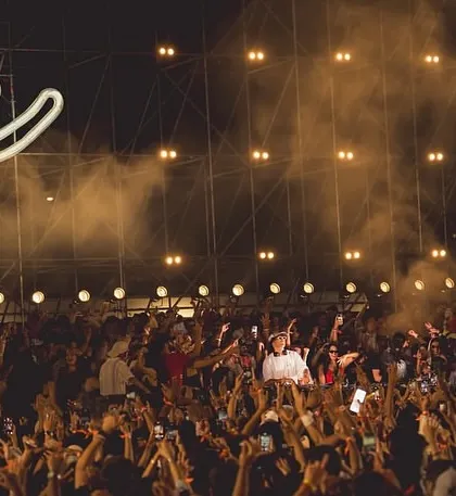 The Keinemusik smiley logo glowing above a massive crowd with their hands in the air. This shot perfectly captures the collective joy and energy of the night.