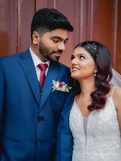 A classic wedding portrait where the couple looks at each other with love. The groom's blue suit and the bride's white dress create a beautiful color contrast.