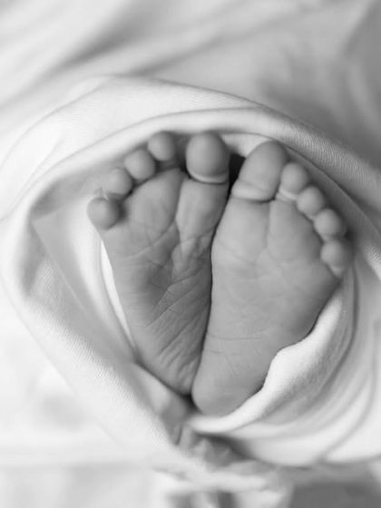 A beautiful black and white photo of a newborn's feet, wrapped snugly in a soft blanket.