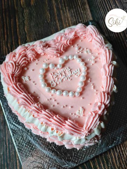 A tamer version of the vintage Marie Antoinette cake. This pink heart-shaped cake is decorated with delicate piping and a pearl-like heart for a birthday.