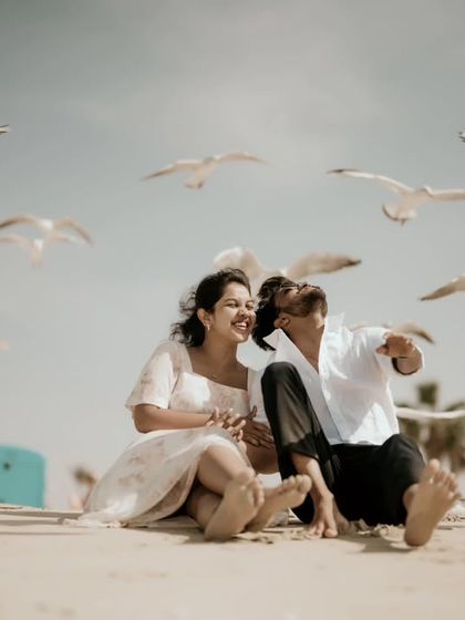 A candid and joyful moment on a beach in Dubai, with seagulls flying overhead.