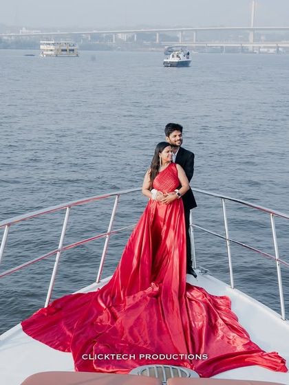 An intimate embrace on the bow of a yacht, the bride's red gown contrasting beautifully with the blue water, capturing a romantic destination pre-wedding moment.