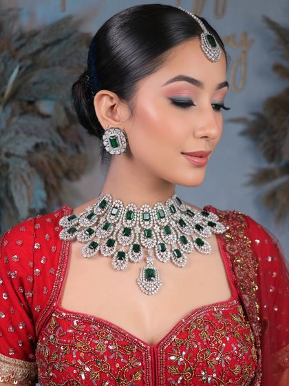 Unveiling bridal elegance that takes your breath away. This look features a clean, sophisticated bun and soft, glowing makeup that complements the diamond and emerald jewelry.