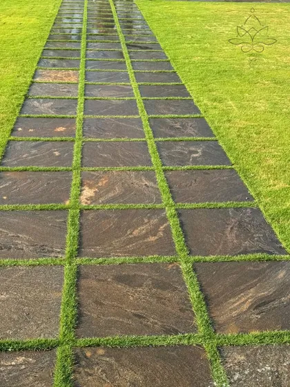 The details matter in landscape design. This pathway combines dark, marbled granite slabs with strips of vibrant green grass, creating a beautiful and durable surface that merges hardscape and softscape elements seamlessly.