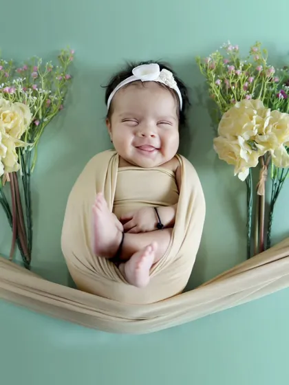 Sometimes, the most beautiful moments are the simplest. We captured this newborn's heart-melting smile, framed by delicate flowers, showing the pure joy and innocence of a new life.