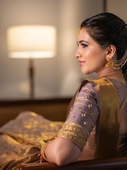 A beautiful profile shot that showcases the flawless skin finish and the elegant hairstyle, adorned with traditional accessories.