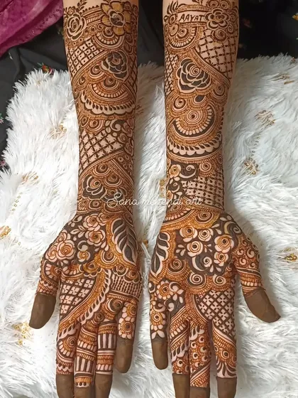 The name 'Aayat' is beautifully written on the wrist, as part of a full and intricate bridal mehendi design.