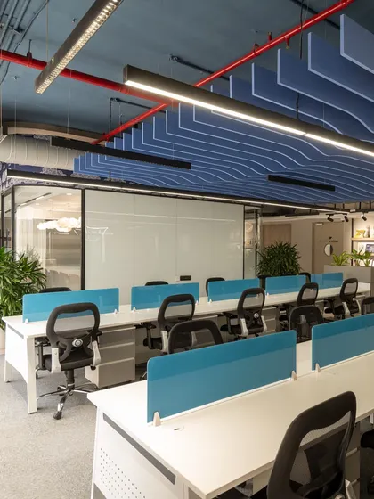 An open-plan office needs to feel both collaborative and organized. For EaseMyTrip, I used a beach-inspired theme with a wave-like acoustic ceiling in a calming blue. This not only manages sound but also visually defines the workspace, while ample greenery and clean desk lines promote productivity and well-being.