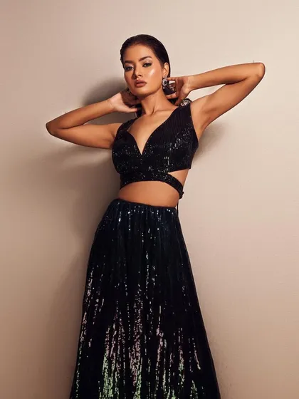 A powerful pose that showcases the full effect of the look. The shimmering black outfit and the dramatic makeup come together for a stunning result.