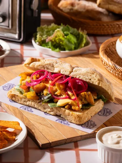 A ciabatta sandwich with pickled onions. The vibrant colors of the filling contrast with the rustic bread.