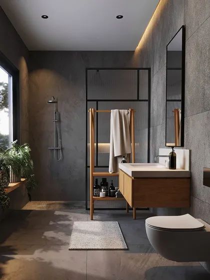 A minimalist bathroom featuring clean lines and natural materials. The space combines large-format grey tiles, a floating wooden vanity, and a simple glass partition for the walk-in shower, with a large window providing ample natural light and a connection to the outdoors.