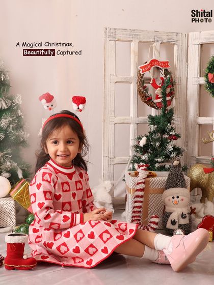 A magical Christmas, beautifully captured. This toddler is all smiles in her festive dress, surrounded by presents, trees, and a snowman.