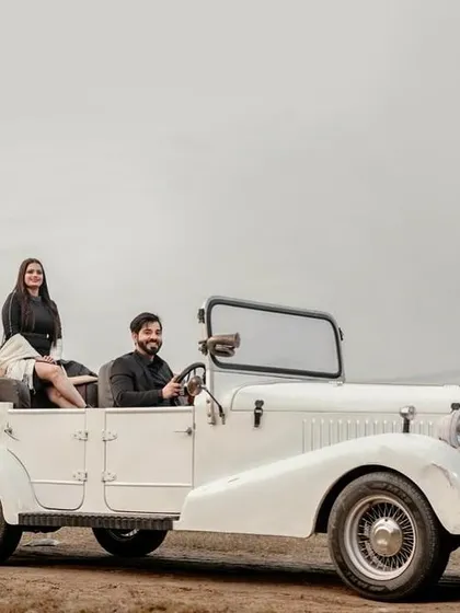 Pre-wedding shoots are all about telling your unique story. For this session, we used a vintage car to create a classic, cinematic feel. This wide shot captures the couple in a stylish pose, suggesting a journey they are beginning together, perfect for a save-the-date or a wedding album intro.