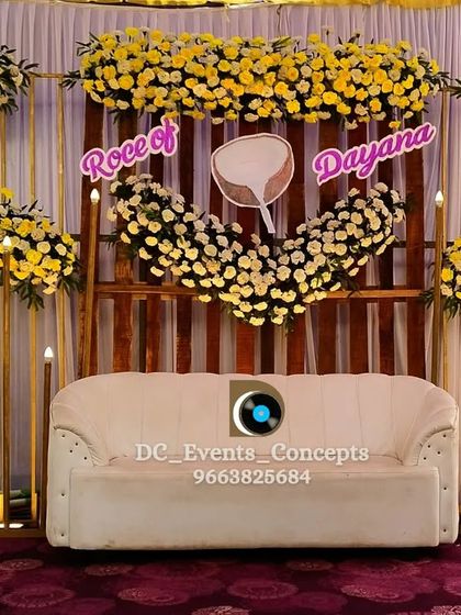 A bright and cheerful Roce ceremony stage, using yellow and white flowers against a rustic wooden backdrop. The custom coconut motif adds a personal, traditional touch.