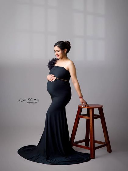 A standing pose by a stool, this shot in a simple black gown is all about quiet confidence and the beauty of the pregnant form.