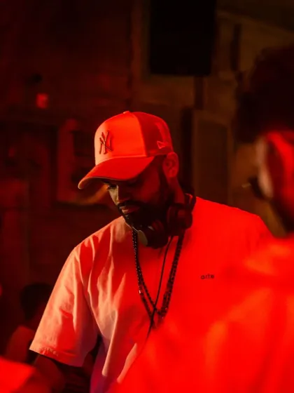 A close-up shot of me in a red-lit club, focused on the mix. This captures the technical side of my performance, ensuring every transition is perfect.