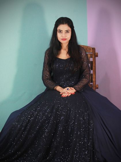 A seated portrait in the navy blue gown, showing off its shimmer and classic silhouette.