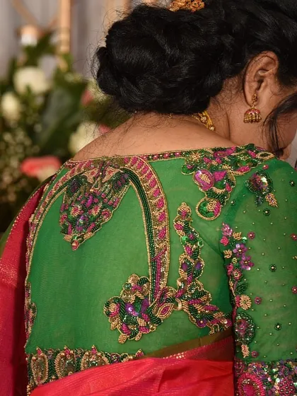 A view of the intricate back design of the green netted blouse. The embroidery pattern creates a beautiful frame, making this a statement piece.