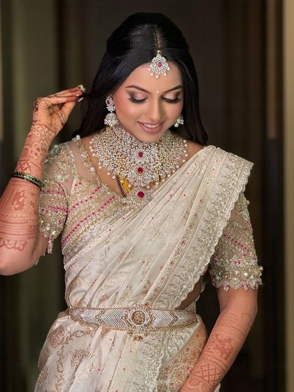A lovely candid moment of the bride adjusting her hair, showcasing her beautiful smile and the flawless makeup.
