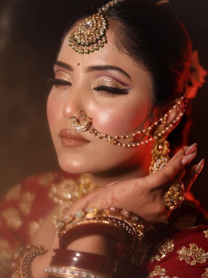 A close-up of a bride with beautiful, shimmery golden eye makeup and a traditional nath.