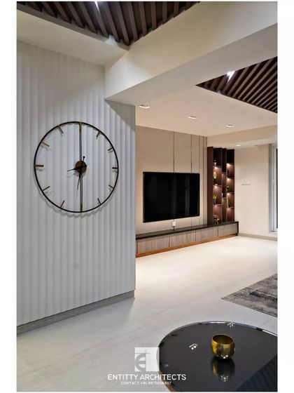 This perspective highlights the fluted wall panel and oversized clock, design elements that add texture and character. The layout provides a clear view of the custom TV unit and display shelves in the background.