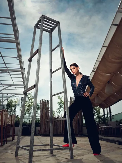 A powerful pose in an industrial-style outdoor setting. The strong lines of the ladder and the model's pose create a visually compelling, high-fashion image.