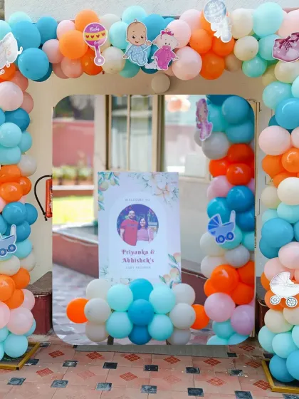A grand entrance for a baby shower. This large balloon arch in pastel shades of blue, orange, and pink is decorated with cute baby-themed cutouts, creating a festive welcome for guests.