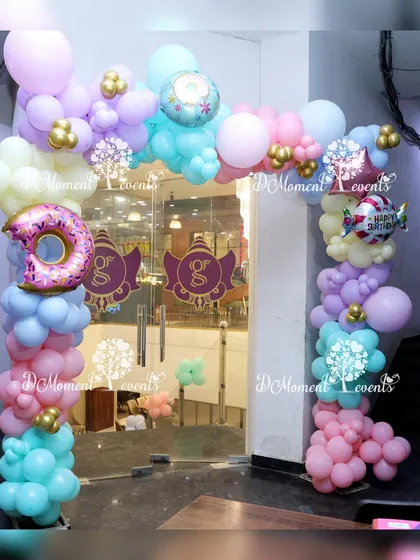 An entrance arch for the Candyland party, made of pastel balloons and accented with large donut foil balloons. This creates a fun and inviting entryway for guests.