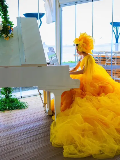 A pianist in a dramatic yellow gown plays a white grand piano. This artistic performance added a touch of surreal elegance to the Istanbul celebration.