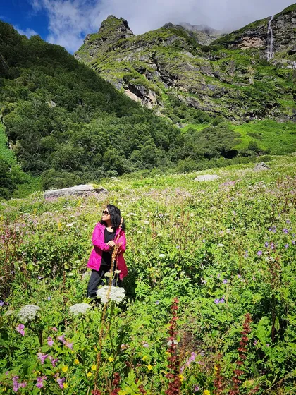 Another shot from the Valley of Flowers, this time with the pink jacket fully on, showing a practical and vibrant trekking look.