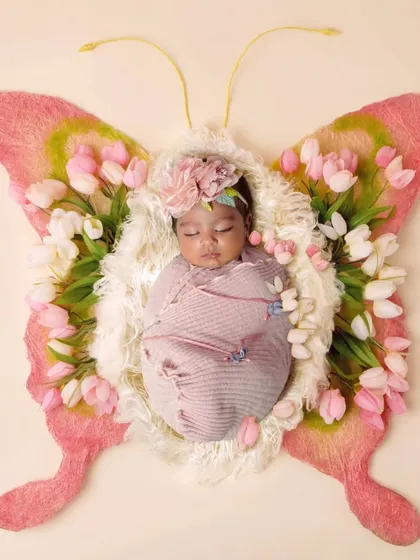 A creative newborn shot where the baby is the body of a beautiful butterfly made of flowers.