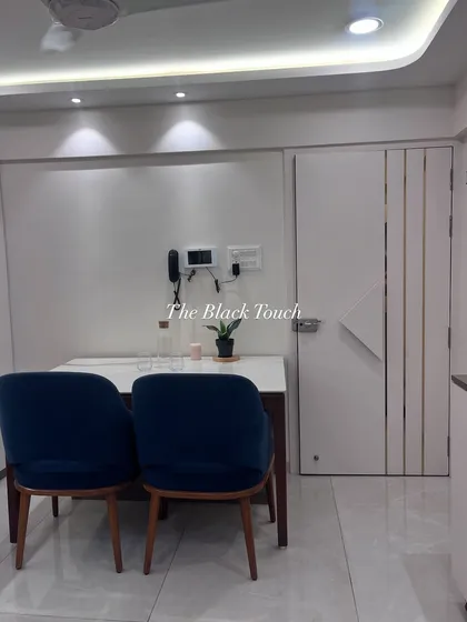 This image shows the dining area with a clean, minimalist aesthetic. The simple white table and dark blue chairs are complemented by a sleek, modern safety door, ensuring security without compromising on style.