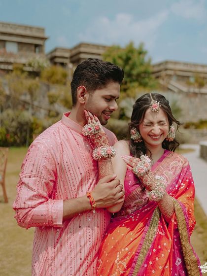 A playful and candid moment where the bride is applying Haldi to the groom's cheek, both sharing a laugh.