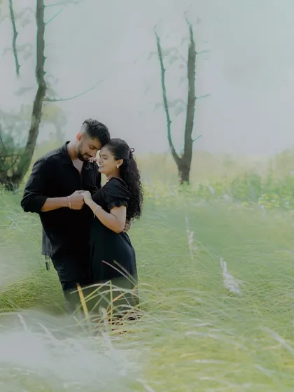 A dreamy and hazy pre-wedding photo of a couple in a field of tall grass, creating a soft and romantic mood.