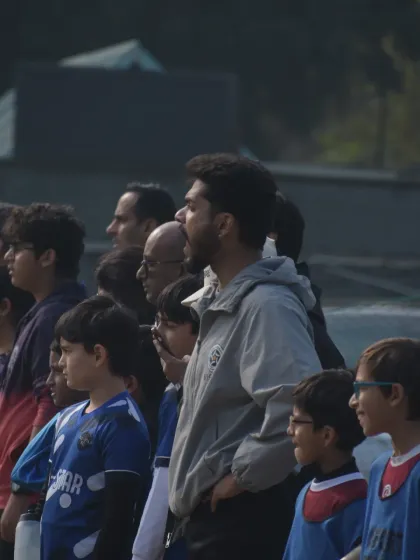 A coach watches intently from the sidelines with parents and players. We are a community of players, coaches, and families all invested in the journey.
