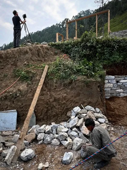 Documenting our work is a collaborative process. Here, a photographer frames a shot of the stone masons at work, capturing both the craft and the challenging terrain of our Himalayan site.