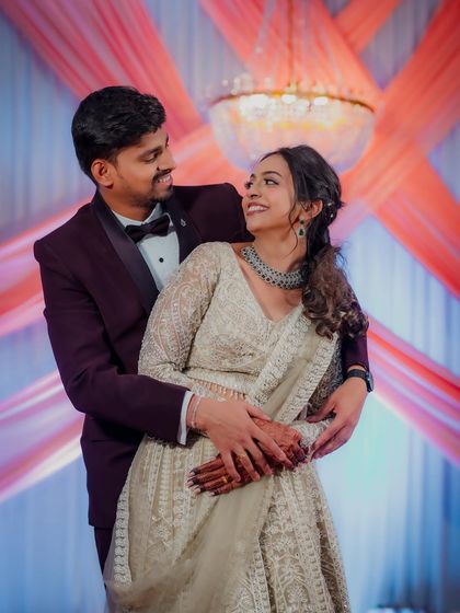 Kasturi and Nikhil share a loving gaze during their engagement shoot. The grand chandelier and elegant decor add a touch of glamour to this romantic portrait.