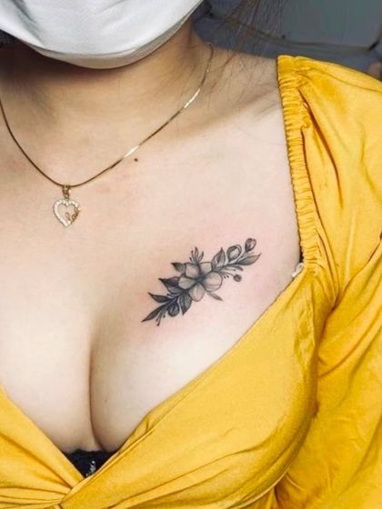 A delicate floral bouquet tattoo on the chest. The black and grey shading gives the flowers a soft, realistic look.