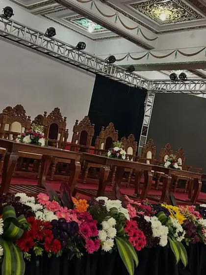 Our floral arrangements are designed to complement the event's formality. Here, a long, multi-colored floral runner lines the front of the stage, and a large arrangement adorns the official lectern, which features the Government of Karnataka emblem.