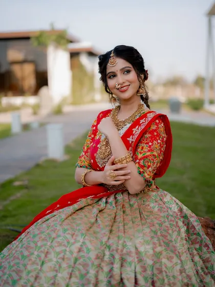A seated portrait of actress Niveditha Gowda in a beautiful half saree. The garden setting and her graceful pose create a classic and elegant image.