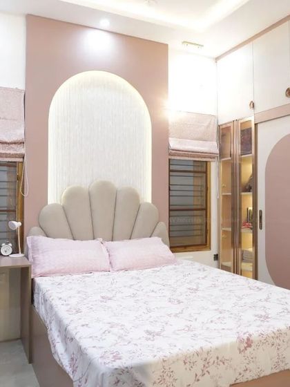 A charming kids' room with a pink theme, featuring a shell-shaped headboard and arched wall details.
