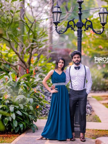 A stylish couple poses by a classic lamppost in our garden, a simple yet elegant setting.