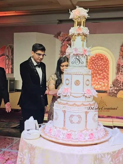 A close-up of the couple during their cake-cutting ceremony, showing the detailed tiers and the personalized monogram that made this cake uniquely theirs.