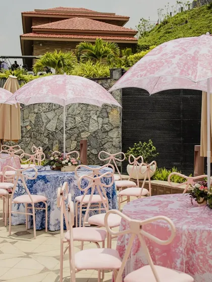 Dior-inspired prints on tablecloths and umbrellas, paired with pink bow-tie chairs, for a chic and fashionable 'Carnival of Love'.