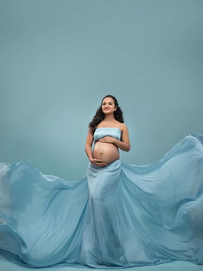 A slightly different angle of the blue gown fabric toss, capturing a look of happy anticipation.