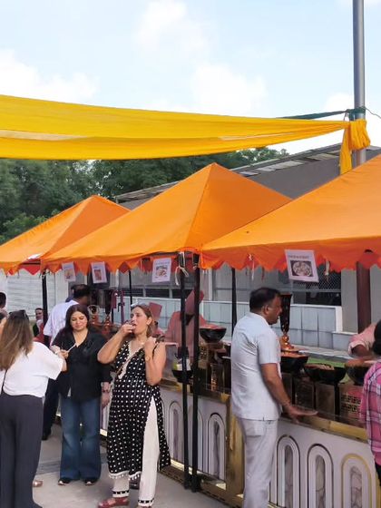 Guests enjoying our food at a vibrant outdoor event. We set up multiple stalls with colorful canopies, creating a festive, market-like atmosphere for everyone to explore different cuisines.