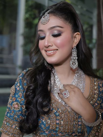 A glowing, fresh glam makeup look. The shimmery blue eyeshadow and glossy lip make her look like a star.