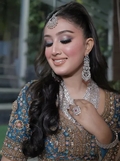 A glowing, fresh glam makeup look. The shimmery blue eyeshadow and glossy lip make her look like a star.